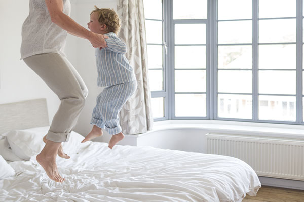 madre e hijo saltando felices encima de la cama