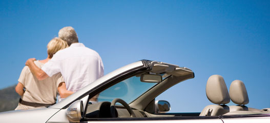 pareja mayor sentados en capó del coche