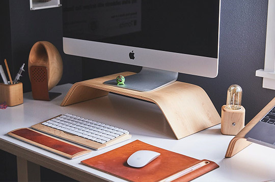 Escritorio con ordenador, altavoz, teclado y bolígrafos