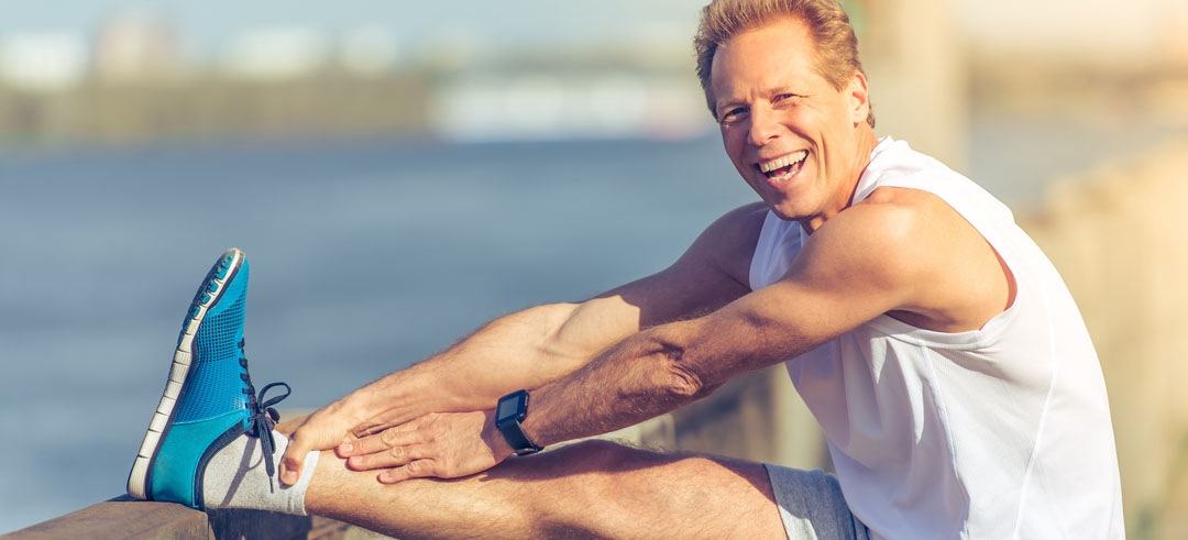 Hombre sonriente mientras estira una pierna